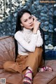 A woman sitting on top of a brown couch.