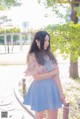 A woman in a blue skirt is standing in a park.