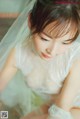 A woman in a wedding dress sitting on the floor.