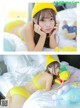 A woman in a yellow bikini laying on a bed with stuffed animals.