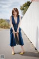 A woman in a blue dress and yellow shoes posing for a picture.