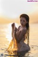 A woman in a white dress sitting in the water.