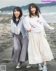 Two young women standing next to each other on a beach.