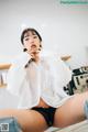 a woman in a white shirt and black panties sitting on a counter