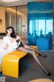 A woman sitting on a yellow bench in a hotel room.