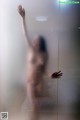 A naked woman standing in front of a glass door.