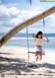 A young girl is swinging on a swing on the beach.