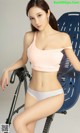 A woman in a pink top and white panties sitting on a bike.