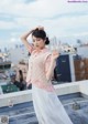 A woman standing on top of a roof next to a building.