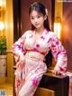 A woman in a pink kimono sitting on a table.