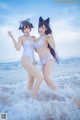 Two women in white bathing suits standing in the ocean.