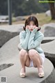 A woman sitting on a stone bench with her hands on her face.