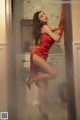 A woman in a red dress and red gloves posing in a bathroom.