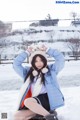 A woman in a blue jacket and white scarf sitting in the snow.