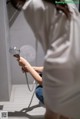 A woman in a white shirt is holding a shower head.