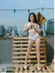 A woman in a white bikini posing on a wooden bench.