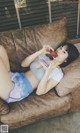 A woman laying on a couch eating a piece of pizza.