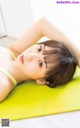 A woman laying on a yellow yoga mat.