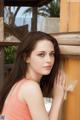 A young woman leaning against a wooden fence.