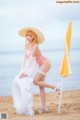 A woman in a bikini and hat posing on the beach.