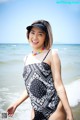 A woman in a black and white bathing suit standing in the ocean.