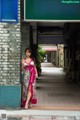 A woman in a long dress standing in front of a building.