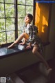 A woman sitting on a window sill in front of a window.