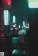 A woman in a white dress is walking down the street at night.