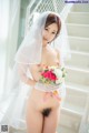 A naked woman in a wedding dress holding a bouquet of flowers.