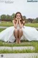 A woman in a white dress sitting on the grass.